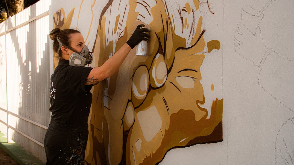 Artista Bruna Rison realizando o grafite
